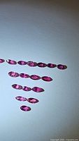Multiple marquise cut rubies laid out in rows on a white background, showing color and clarity