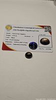 Photo of rectangular certification card from Chanthaburi Gemological Laboratory with gemstone placed nearby showing natural star sapphire details.