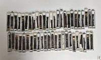 Full lot of approximately 50 black leather watch straps in original packaging, laid out flat.
