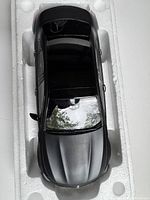 Top-down view of the black matte Mercedes Benz diecast model in styrofoam packaging, showing intact hood, windshield, and roof.