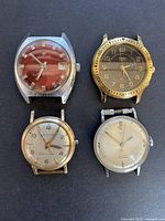 Four vintage men's watches with visible wear, various brands including Bulova, Timex and Jupiter.