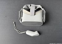 Top view of Oculus Meta Quest VR headset with controller lying in front of it, showing head straps and wrist strap on controller.