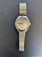 Full view of vintage Citizen men's watch with stainless steel linked bracelet on black background.