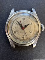 Front view of the vintage Crest watch showing aged dial, black hour numerals, red seconds hand, and black hour and minute hands.