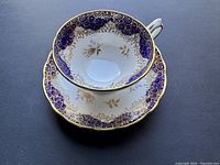 Porcelain bone china cup and saucer set with cobalt blue and gold ornate floral pattern, showing inside and top view.