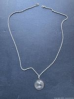 Full view of silver necklace with Aries zodiac pendant showing chain and missing clasp.