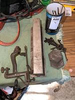 Photo of antique cast iron apple peeler, aluminum track piece, lead weights, can of old square nails, and skeleton keys on table.
