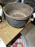 Another angled top view showing the large opening of the cauldron with wire handle attached for carrying.