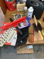 Wide view of lot items on wooden table including Wahl clipper kit, dubbin, thermometers, brushes, reflector and safety vest