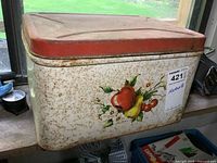 Vintage metal tin container with fruit decal and rust, showing the storage container for diving gear