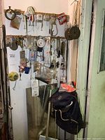 Fishing tackle and gear hung on wall with two blue backpacks below. Includes fishing scales, lures, sinkers, bobbers, and vintage net.