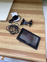 Garmin GPS device with connected car charger and windshield mount on a wood surface.