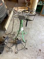 Full view of green metal plant stand showing the five black metal baskets attached, illustrating the overall structure and detail of the lot.