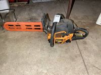 Side angle showing full length of chainsaw with orange plastic chain guard on bar.