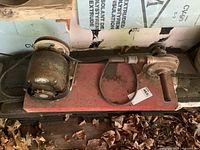 Photo showing top-down view of vintage pump and electric motor mounted on red heavy steel channel with visible wear and missing belt.