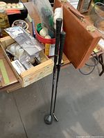 Two golf clubs with black grips labeled King Snake, one iron and one driver club, positioned leaning against a table.