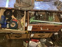 Top-down view inside two open wooden drawers containing assorted hand tools, grips, measuring tapes, bolts, and punches on a workbench.