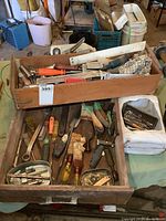 Two wooden drawers containing mixed hand tools including scrapers, files, chisels, and other items spread loosely inside, showing wear and use.