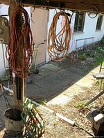 Outdoor area with hanging orange and yellow extension cords and tire traction plates on ground.