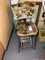 Front view of vintage chrome frame seat with floral upholstery and flip-out step stool.