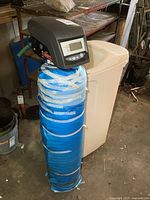 Full view of assembled water softener system showing digital head, resin tank wrapped in blue tape, and beige brine tank
