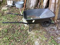 Side view of the black Erie wheelbarrow showing the resin tub, metal frame, and single wheel.