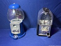 Both gumball machines side by side on a blue cloth background showing their shape and condition.