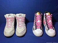 Front view of both pairs of girls youth Nike shoes in size 7.5 US, showing pink accented Air Force 1s on the left and graffiti-style high tops on the right.