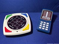 Round electronic skill game with colored sections and central display showing a grid pattern labeled with words
