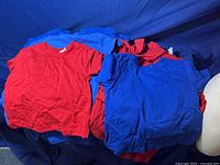 T-shirts laid out grouped by red and blue colors on a blue background, showing multiple pieces stacked together.