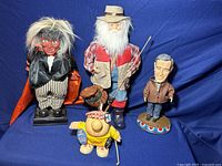 All four character statues and dolls in one frame on blue background