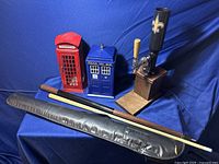 Full view of the lot showing two telephone booth decorations (red British phone box and blue police box), bottle service stand with beer tap handle, pool cue and its black carrying case.