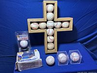 Jackie Robinson vinyl figure in original box with visible water damage and wear, 3 signed baseballs including Mark McGwire, wooden cross display with 11 baseballs.