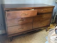 Front angled view of the Mid-Century Modern walnut wood dresser showing six drawers with brass handles, standing on tapered legs.
