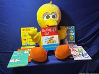 Front view of Big Bird plush toy seated with nine children’s books arranged around it.