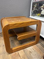 Angled view showing the table's rounded edges, two levels, and wood grain pattern.