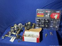 Various door knob sets in different finishes including black and brass, some packaged in plastic and cardboard boxes with keys and hardware.
