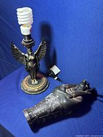 Egyptian-style lamp with a winged god figure base and CFL bulb on a blue background
