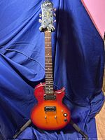 Full front view of the Epiphone guitar on a stand showing the entire body and neck with sunburst color.