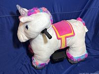 Front side view of large plush unicorn ride-on toy with pink saddle and multicolor mane and tail.