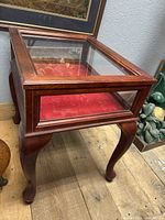 Side angled view of display table showing top glass panel and red fabric interior.