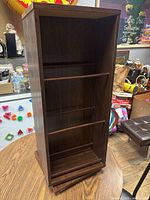 Front view of wooden bookcase showing three shelves and lazy Susan base.