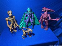 Four alien creature figures arranged on blue background, showing full bodies and different poses