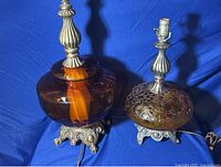 Pair of two distinct style orange globe lamps on ornate metal bases, showing overall condition and design features.