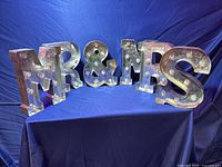 Full set of 7 metal marquee light letters spelling 'MR & MRS' on blue cloth background.