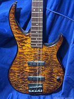 Close-up of the body showing the quilted maple veneer over basewood with pickups and control knob, highlighting wood grain and finish details.