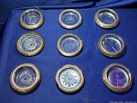 Top-down view of all nine sterling silver rimmed crystal coaster cup holders arranged in three rows.