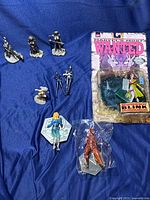 Photo showing all collectible figures and one in packaging on a blue fabric background.