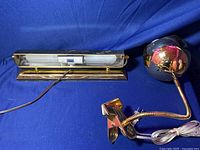 Image showing both lamps, the clip-on gold orb lamp with a flexible neck and clip, and the brass fluorescent desk lamp with a gold-tone base