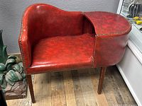 Front and side view of vintage red vinyl phone chair showing curved backrest and nailhead trim